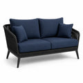 Dwuosobowa sofa ogrodowa z granatowymi poduszkami i plecionką